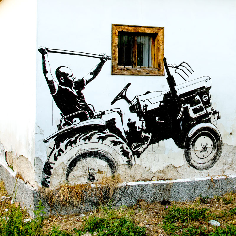 Street art von einem Traktorfahrer mit Mistgabel